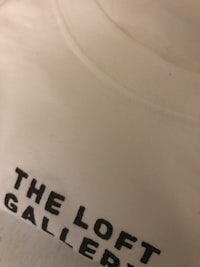 a white t - shirt that says the loft gallery