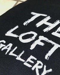 the loft gallery logo on a black t - shirt