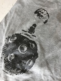 a grey t - shirt with an image of a moon on it